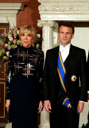 Brigitte Macron a arboré une robe bleu marine, sublimée de motifs couleur argent et bronze sur la poitrine.