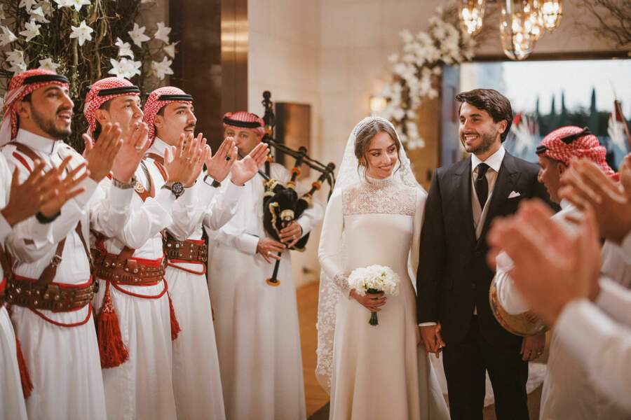 La princesse Iman de Jordanie et son mari Jameel Alexander Thermiotis passent dans une haie d'honneur lors de leur mariage à Amman le 12 mars 2023