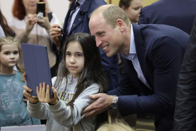 Le prince de Galles pose pour des photos avec un jeune résident ukrainien lors d'une visite dans un centre d'hébergement à Varsovie.