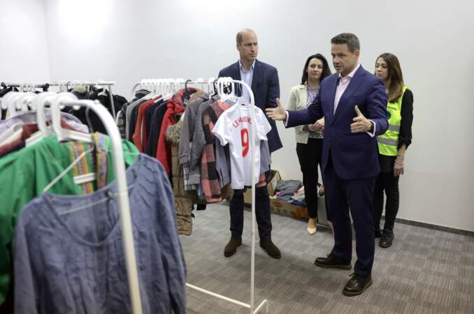 Le maire de Varsovie, Rafał Trzaskowski (deuxième à droite), présente le don de vêtements que le centre a reçu et distribué via une "boutique gratuite" lors d'une visite dans un centre d'hébergement.