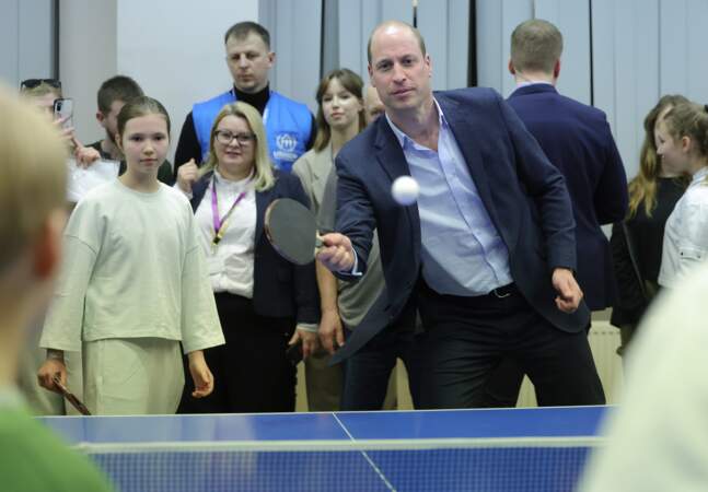 Le prince William joue au tennis de table lors d'une visite dans un centre d'hébergement à Varsovie.