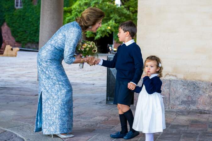 La reine Silvia de Suède salue les deux enfants présents sur le lieu d'arrivée