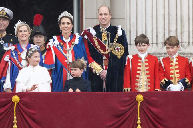 Le duc d'Édimbourg, Lady Louise Windsor, le vice-amiral Timothy Laurence, la princesse Charlotte, le prince Louis, Kate la princesse de Galles, William le prince de Galles et les pages d'honneur, dont le prince George (à l'extrême droite), posent sur le balcon du palais de Buckingham, à Londres, après le couronnement.