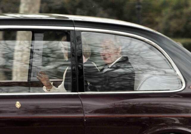 Le roi Charles III d'Angleterre prend le temps de sourire à la foule à travers la vitre de la voiture. 