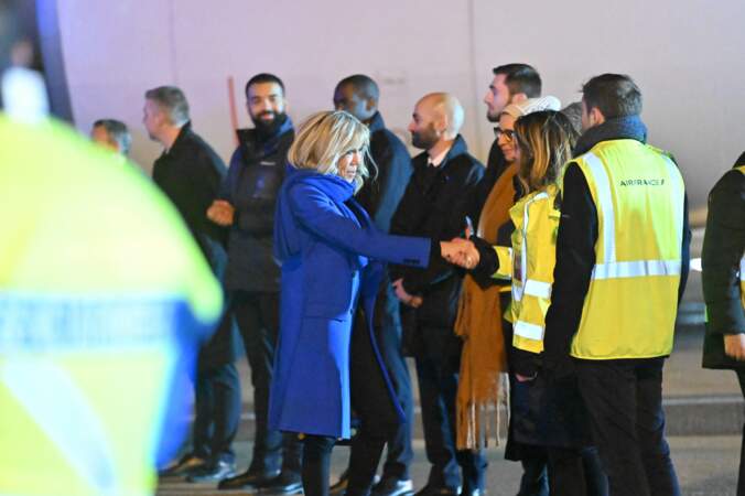 Brigitte Macron se trouve sur le tarmac de l'aéroport pour serrer la main aux personnes qui forment une  haie d'honneur devant elle