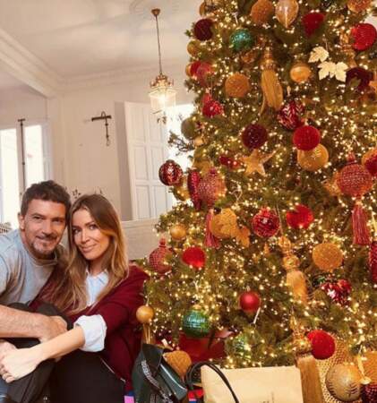 Antonio Banderas pose aux côtés de sa chérie devant un sapin de Noël agrémenté de plein de cadeaux.