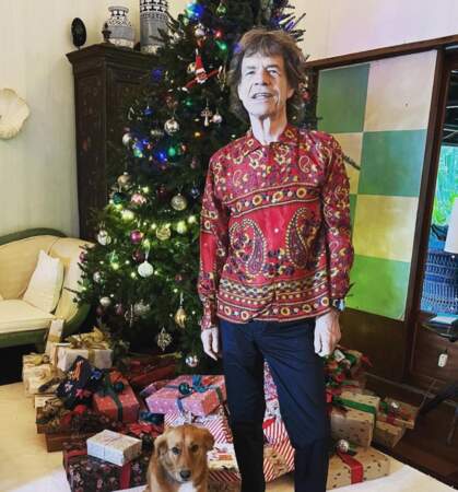 Mick Jagger prend l'attitude d'un rockeur hippie devant son sapin de Noël rempli de cadeaux.