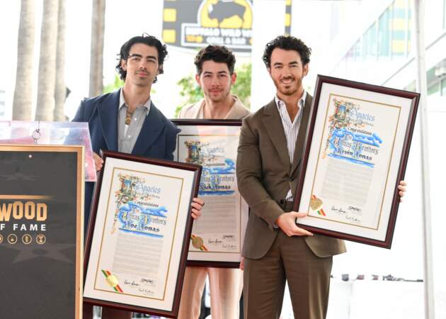 Chacun des Jonas Brothers tient dans sa main le contrat validant l'apposition de l'étoile