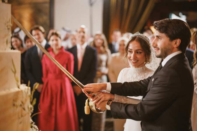 La princesse Iman de Jordanie et son mari Jameel Alexander Thermiotis coupent le gâteau à l'aide d'un sabre lors de leur mariage à Amman le 12 mars 2023