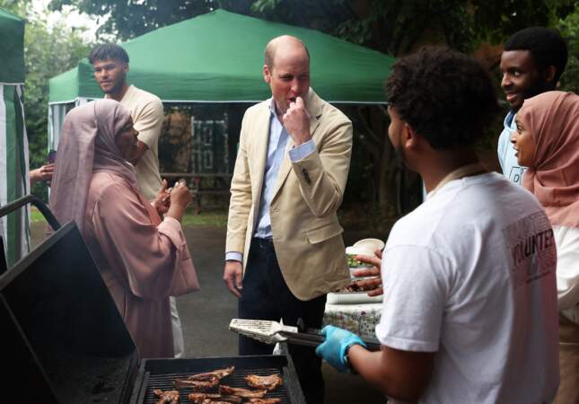 Le prince William discute avec les membres de l'association pendant qu'ils préparent un barbecue