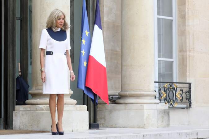 Brigitte Macron attend la première dame sur le parvis de l'Élysée, les cheveux au vent