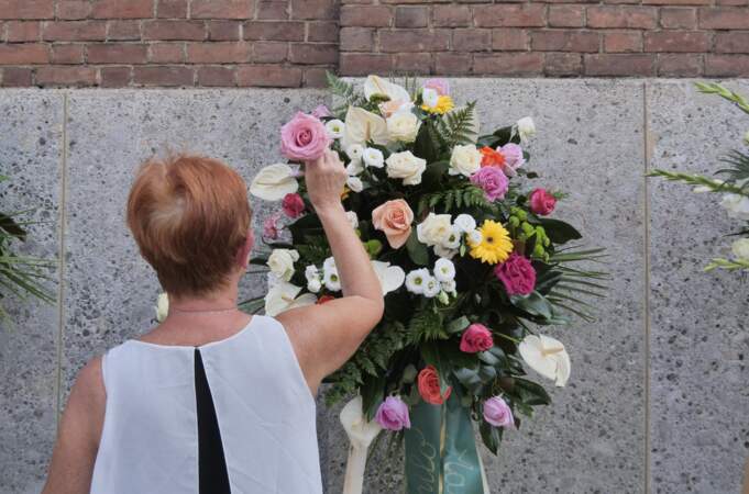 Les personnes venues lui faire un dernier adieu lui rendent hommage avec des fleurs.
