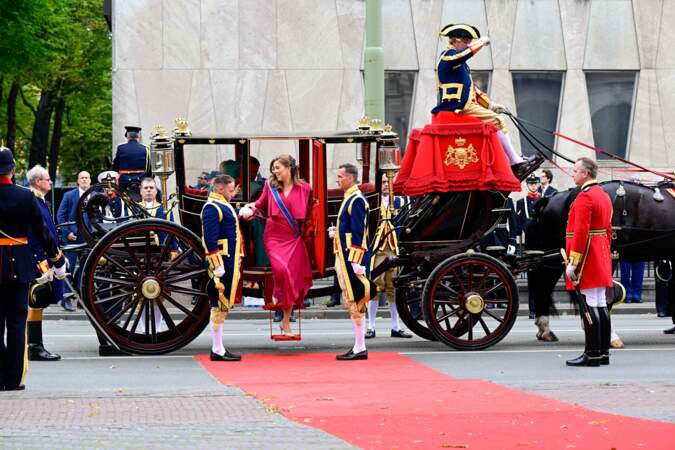 Elle descend du carrosse avec l'aide des assistants de la famille royale portant la tenue traditionnelle