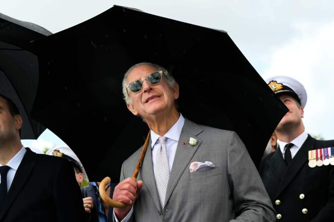 Le temps ne semble pas clément et le roi se protège avec un grand parapluie noir