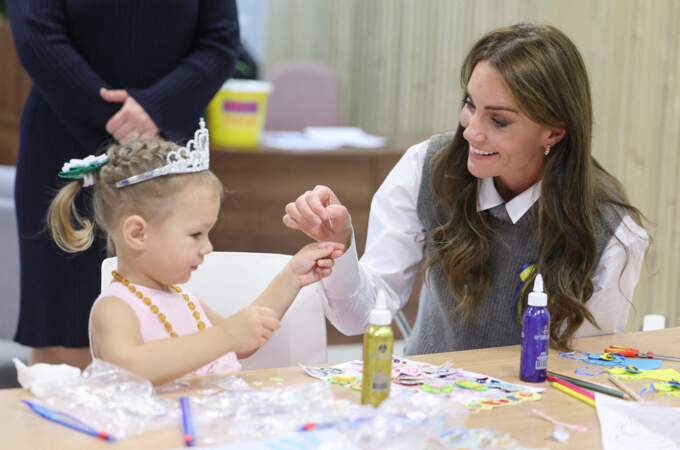 La princesse de Galles sourit en aidant une jeune fille lors d'une séance d'art et d'artisanat au cours d'une visite au centre communautaire Vsi Razom.