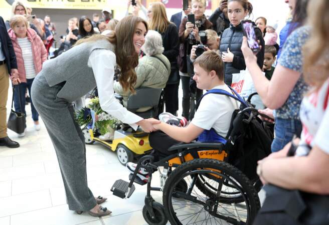 Kate Middleton sourit et serre la main d'une personne en fauteuil roulant lors d'une visite au centre communautaire Vsi Razom dans le centre commercial Lexicon à Bracknell.