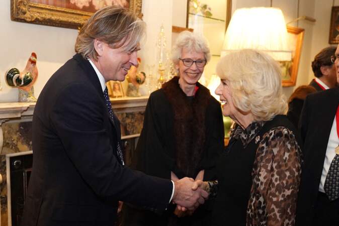 La reine Camilla salue le créateur de mode Stewart Parvin avant la cérémonie.