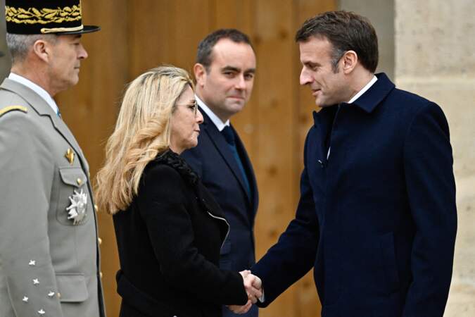 Le président Emmanuel Macron salue la secrétaire d'État chargée des anciens combattants et de la mémoire Patricia Miralles lors d'une cérémonie militaire de prise d'armes dans la cour de l'hôtel national des Invalides à Paris.