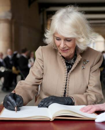 La reine Camilla écrit un mot dans le livre d'or