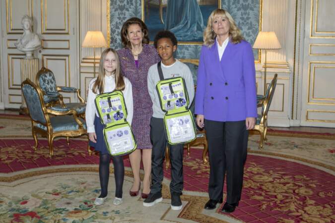 La reine Silvia pose avec les deux enfants et la représentante de l'association