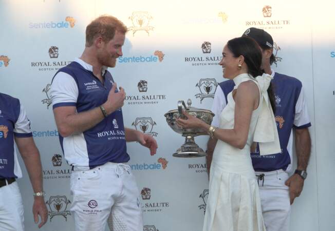La duchesse de Sussex présente le trophée à son mari, le duc de Sussex, après la victoire de son équipe, la Royal Salute Sentebale Team, sur la Grand Champions Team, lors du Royal Salute Polo Challenge.