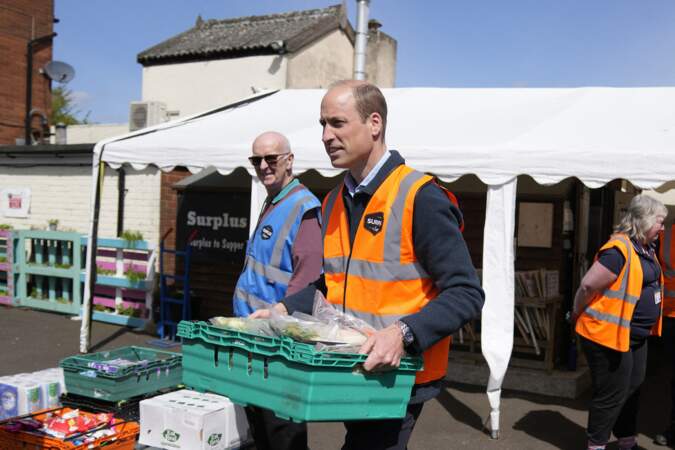 Le prince de Galles aide à charger des plateaux de nourriture dans des camionnettes lors d'une visite à Surplus to Supper.